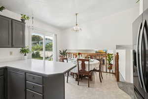 Kitchen featuring a peninsula, fridge with ice dispenser, light countertops, pendant lighting, and a textured ceiling