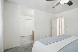 Carpeted bedroom featuring ceiling fan and a closet