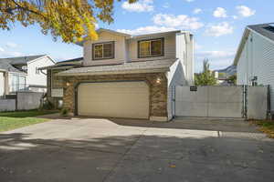 Traditional-style house with a gate, brick siding, concrete driveway, and a garage