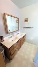 Bathroom with double vanity and light flooring