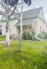 Bungalow-style house with covered porch, a front yard, and a shingled roof