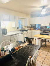 Kitchen with light countertops, white cabinets, light tile patterned floors, and appliances with stainless steel finishes