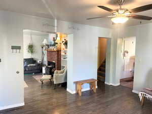 Sitting room featuring dark wood-style floors, ceiling fan, and a fireplace