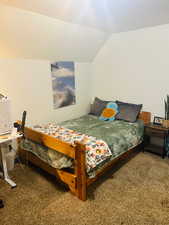Bedroom with vaulted ceiling and dark carpet