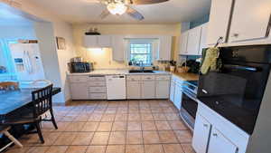 Kitchen featuring black appliances, white cabinetry, light countertops, a ceiling fan, and light tile patterned floors