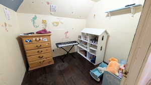 Bedroom with dark wood-style floors and vaulted ceiling