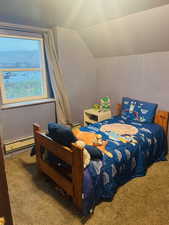 Carpeted bedroom featuring vaulted ceiling and baseboard heating