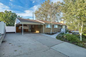 Ranch-style home featuring driveway, a carport, brick siding, and a shingled roof