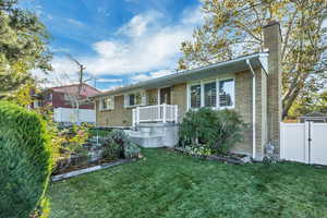 Single story home featuring a garden, brick siding, a chimney, and a gate