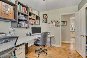 Home office with light wood-style flooring and built in study area
