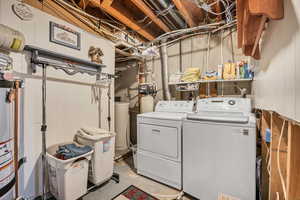 Laundry area with concrete flooring, washer and dryer, and water heater