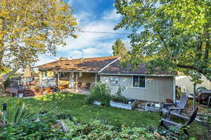 Back of property featuring a garden, a lawn, roof with shingles, a wooden deck, and a patio