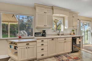 Kitchen featuring cream cabinets, plenty of natural light, black dishwasher, and light tile patterned floors
