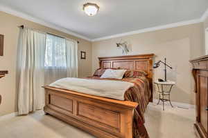 Bedroom with ornamental molding and light carpet