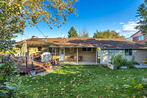 Back of property featuring a yard, a deck, a patio area, brick siding, and a chimney