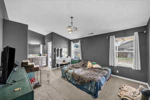 Bedroom with carpet, vaulted ceiling, connected bathroom, a chandelier, and a textured ceiling