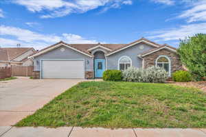 View of front of home with stone siding, stucco siding, a front lawn, and driveway