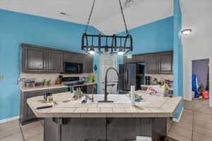 Kitchen featuring light tile patterned flooring, black appliances, a kitchen bar, tasteful backsplash, and high vaulted ceiling