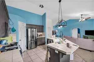 Kitchen featuring tile countertops, backsplash, light tile patterned floors, an island with sink, and open floor plan