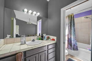 Bathroom with shower / bath combo with shower curtain, vanity, and tile patterned flooring