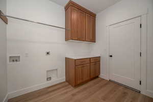 Washroom featuring electric dryer hookup, light wood-type flooring, cabinet space, and hookup for a washing machine