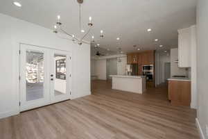 Kitchen featuring a ceiling fan, decorative light fixtures, open floor plan, light countertops, and brown cabinetry