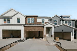 View of front of home with an attached garage, concrete driveway, and board and batten siding