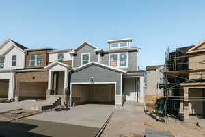 View of front facade with driveway, board and batten siding, and stone siding