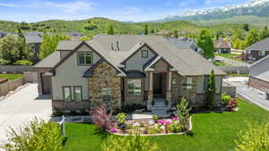 View of front facade with concrete driveway, a mountain view, stone siding, a residential view, and a garage