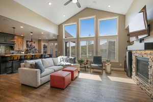 Living room with high vaulted ceiling, dark wood finished floors, recessed lighting, a fireplace, and ceiling fan