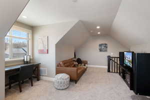 Living room with light colored carpet, recessed lighting, lofted ceiling, and a desk