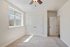 Unfurnished bedroom with light colored carpet, a closet, and ceiling fan