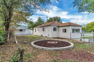 Back of house featuring a shingled roof, a gate, and an outdoor structure