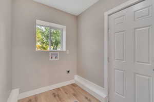 Washroom featuring wood finished floors, washer hookup, and hookup for an electric dryer