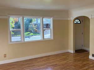 Unfurnished dining area featuring arched entry and wood finished floors
