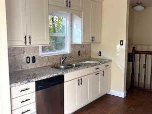 Kitchen featuring dishwasher, granite countertops, decorative backsplash, dark wood-type flooring, and white cabinetry