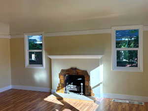 Detailed view of wood finished floors, a stone fireplace, and ornamental molding