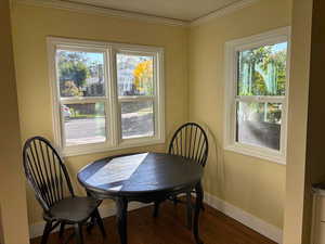 Dining space featuring dark wood-style flooring and ornamental molding