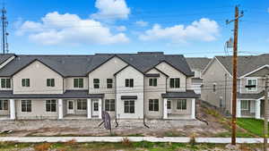 View of front of home with a patio area, stucco siding, and brick siding