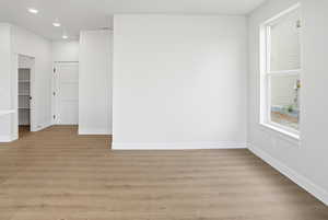 Empty room with light wood-style floors and recessed lighting