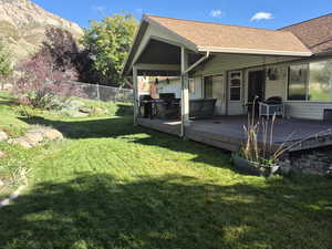 Rear view of house featuring a shingled roof and a wooden deck