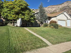 View of front of property with a front yard, an attached garage, stucco siding, and a balcony