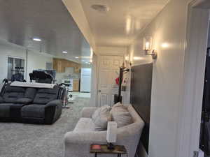 Living area featuring a textured ceiling, recessed lighting, light colored carpet, and light tile patterned floors