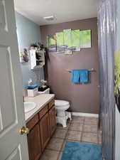 Full bathroom with a textured ceiling, vanity, light tile patterned floors, and a shower with shower curtain