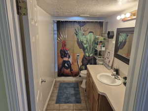 Bathroom featuring vanity, light tile patterned floors, and a textured ceiling