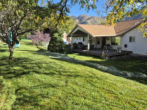 Rear view of property featuring a yard, a deck with mountain view, and roof with shingles