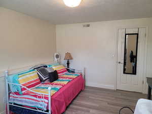 Bedroom with wood finished floors and a textured ceiling