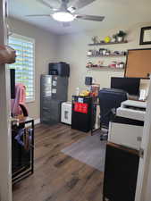 Home office featuring dark wood-type flooring and a ceiling fan