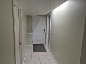 Hallway featuring a textured ceiling and light tile patterned flooring