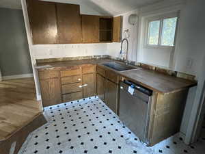 Kitchen with stainless steel dishwasher, light flooring, butcher block counters, and brown cabinetry